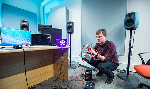 Male student setting up lights in studio three