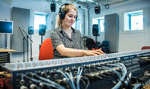 Female student with headphones at the mixing desk in Studio One